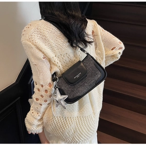 Detail view of tweed and leather patchwork shoulder bag featuring a silver star charm