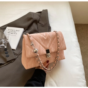 Detail of pink quilted shoulder bag with silver chain strap and metal ball charm