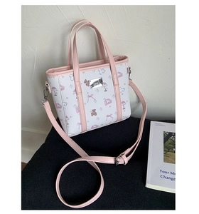 Detail of cartoon bear print tote bag with pink straps and metallic brand plate