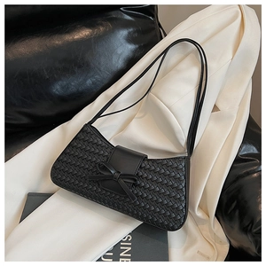 Detailed view of black woven texture and bow flap design on the fashion underarm bag