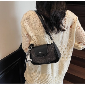 Detail view of the black and grey crossbody bag with star pendant on a model's shoulder