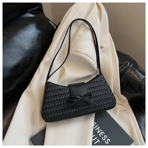 Close-up of black woven leather texture and elegant bow detail on this baguette bag