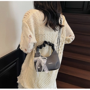 Detail of dark grey checkered handbag with ruffled handle and lace pearl bow ornament