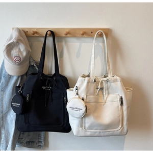 Detail of minimalist canvas tote bags in black and beige with drawstring and mini pouch