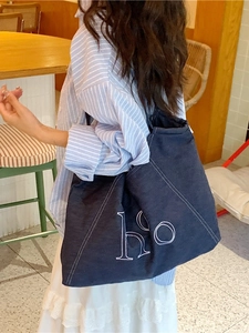 Classic dark blue canvas tote bag with white stitching and embroidery on a model