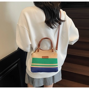 Close-up of tricolor woven handbag with leather straps and striped knit texture