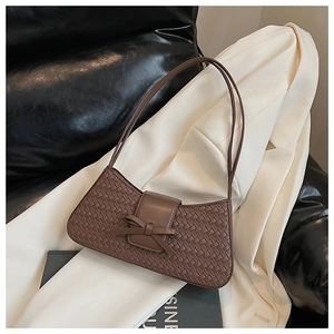Macro view of dark brown woven texture and leather bow detail on the baguette bag