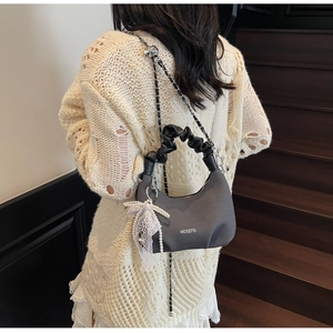 Detail of grey knitted crossbody bag with lace pearl bow and silver chain strap