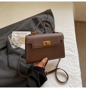 Close-up of a dark brown lychee textured leather bag with retro golden turn-lock closure