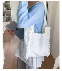 Close-up of white canvas tote bag with elegant lace ruffles and side stitching details