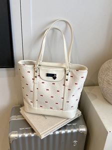 Fresh white floral tote bag with red bow patterns on a silver suitcase