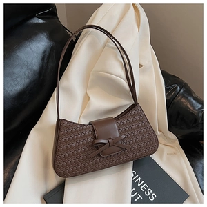 Close-up of woven dark brown underarm bag featuring a stylish leather bow detail
