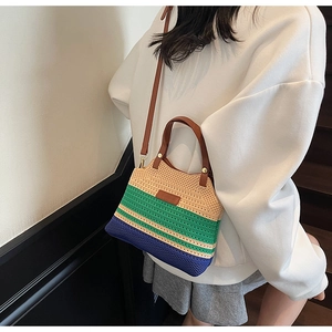 Close-up of a striped knit bucket bag featuring colorful patchwork and brown leather straps