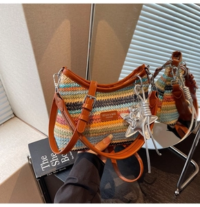 Détail d'un sac de plage tressé à rayures colorées avec bandoulière en cuir et breloque