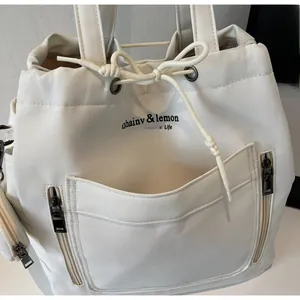 Detail of cream canvas tote featuring large front pocket and silver metal zipper compartments