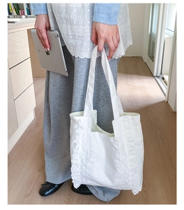 Detail view of large white canvas tote bag with lace pleats being used for student life