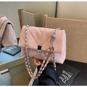 Detail of pink quilted shoulder bag featuring silver chain strap and metal ball accessory