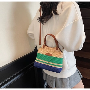 Detailed view of handmade knitted striped bucket bag with leather handles and gold metal buckles