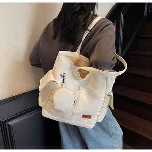 Detail of off-white canvas tote bag with round coin purse and brown leather fashion label
