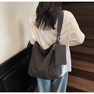 Close-up of a large dark plaid canvas tote bag with adjustable strap and mini pouch