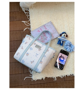Detail of light blue printed bucket bag with cute bear patterns and metal logo plate