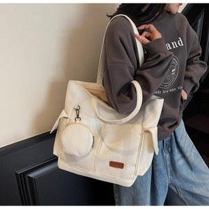 Detail shot of a white large-capacity canvas tote bag with side flap pocket and mini pouch
