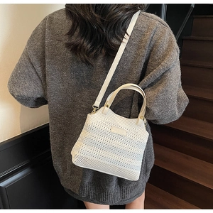 Detailed back view of a model wearing a white knitted mesh bucket bag with leather strap