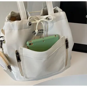 Close-up of white canvas tote bag with drawstring closure and green tablet inside
