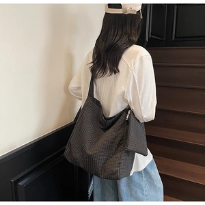 Detail of checkered canvas tote bag with side zipper pocket on a model outdoors