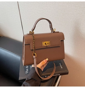 Close-up of dark brown pebble leather handbag with gold metal twist lock and chain strap