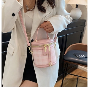 Detail of pink plaid bucket bag showing gold zipper hardware and detachable strap