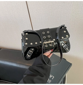 Detail of glossy black patent leather shoulder bag with silver punk rivets and eyelet straps