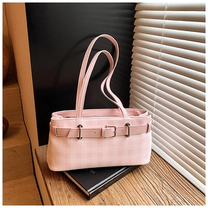 Detail of pink plaid tote bag featuring decorative metal buckle on a minimalist book stand