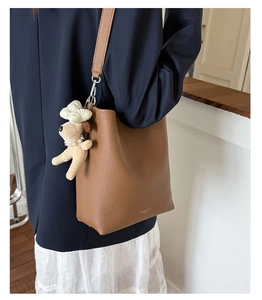 Brown litchi grain leather bucket bag featuring a cute plush puppy pendant detail