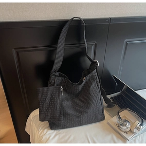 Detail of checkered canvas tote bag with matching small coin pouch on a white bed