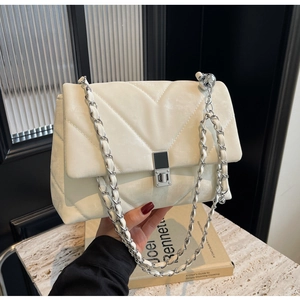 Detail of beige quilted velvet shoulder bag with silver chain and sphere charm
