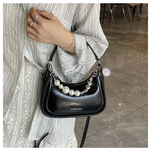 Detail der schwarzen Hobo-Tasche mit Perlenkette und silbernen Beschlägen am Modell