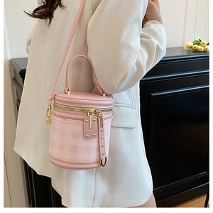 Pink quilted cylinder bucket bag shown on model with gold hardware and shoulder strap