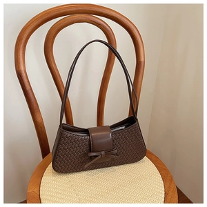 Detail of coffee brown woven PU leather shoulder bag with decorative bow on vintage chair