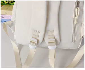 Détail des bretelles rembourrées ajustables et de la fermeture éclair du sac blanc
