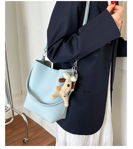 Light blue bucket bag in lychee leather featuring a cute plush dog charm and wide strap