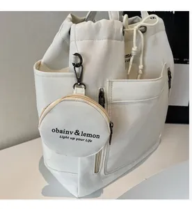 Close-up of a white canvas drawstring bucket bag with a small matching round pouch charm