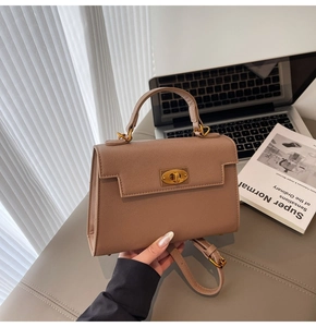 Detail of beige Kelly style handbag with gold twist lock and textured finish