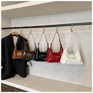 Détail de cinq sacs hobo plissés en demi-lune avec boucles dorées sur un support en métal