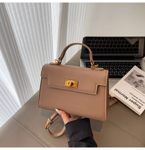 Detail of mocha lychee leather handbag featuring a golden oval twist lock and sturdy handle