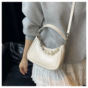 Détail du sac demi-lune beige avec perles décoratives et chaîne en métal argenté