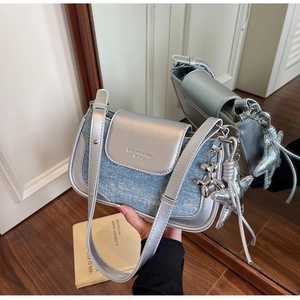Detail of silver metallic leather and light blue denim shoulder bag with star charms