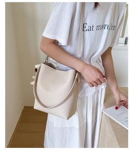 Close-up of cream white bucket bag with pebble leather texture and dual straps