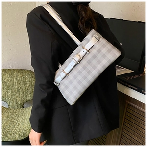 Detail view of grey checkered shoulder bag with silver buckle on a black blazer