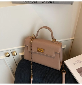 Detail of light brown trapezoid Kelly bag with gold metal chain and twist lock closure